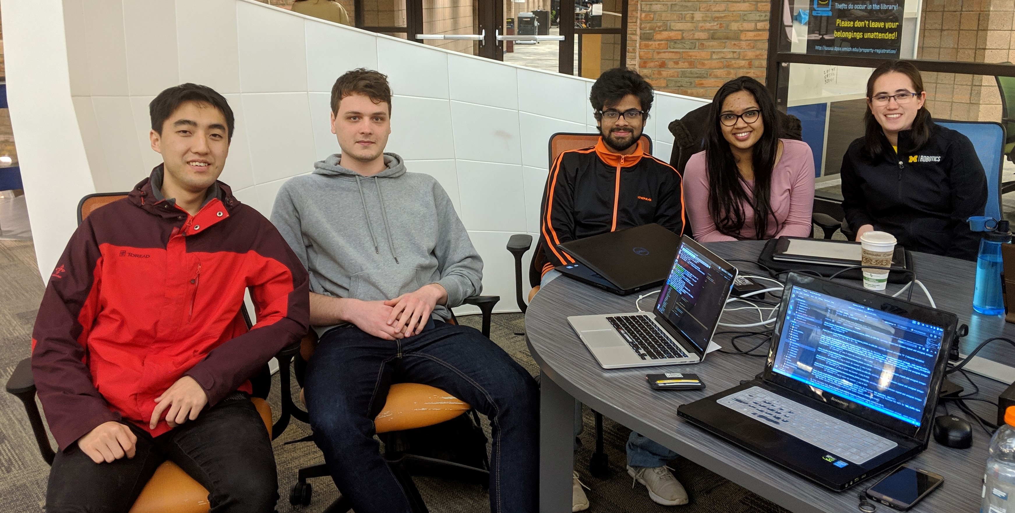 Five people sitting around a shared workstation